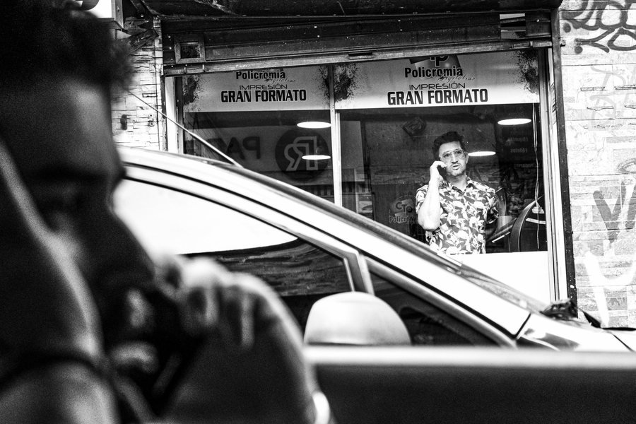 Street scene in Antioquia, Colombia, man on the phone behind a car, black and white