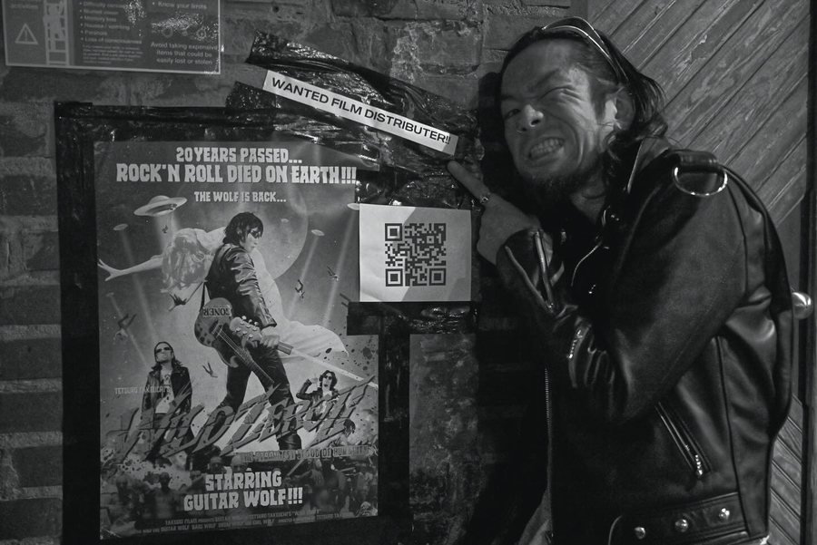 Guitar Wolf beside their tour poster at the 529, East Atlanta